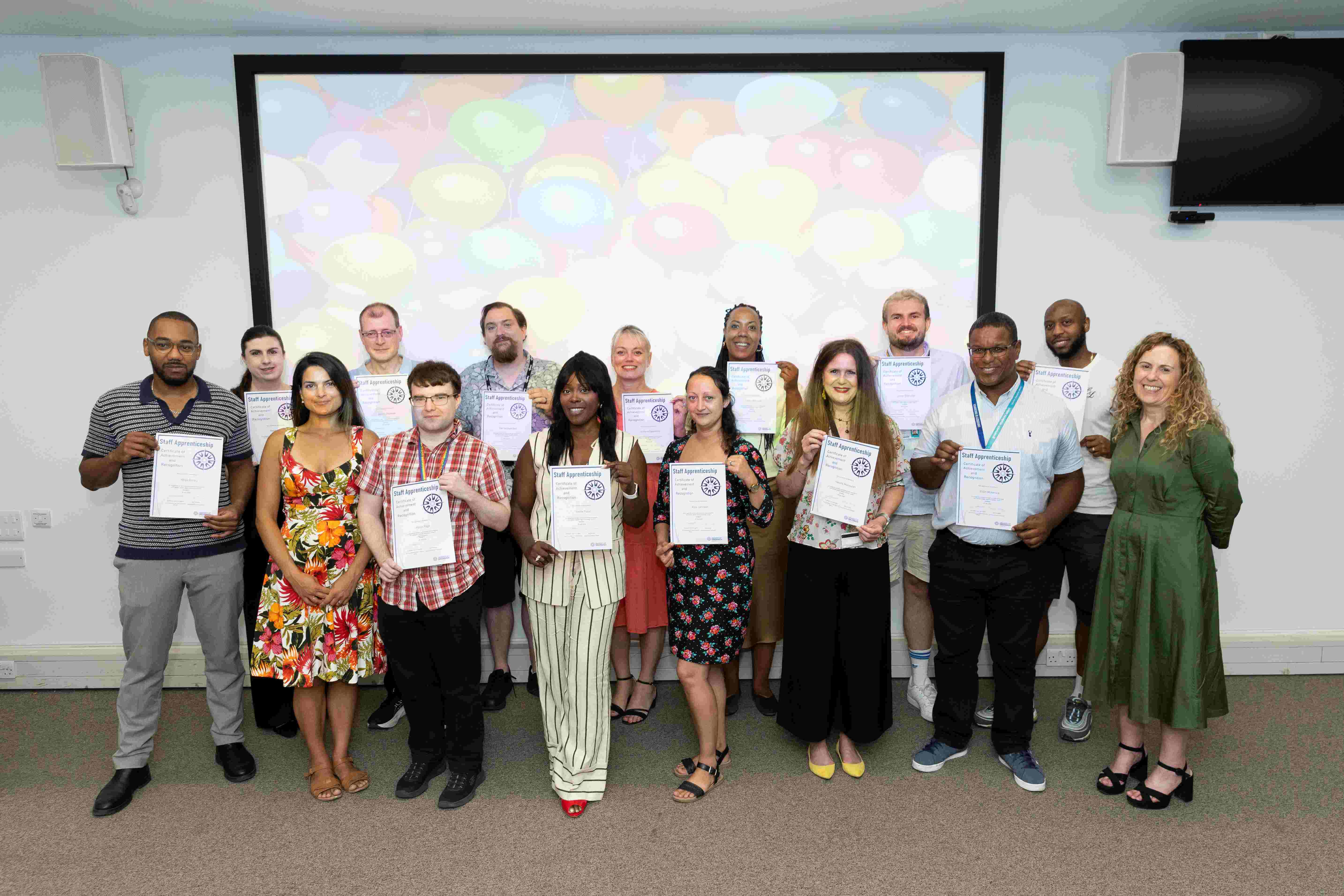 Group of colleagues some holding certificates in an indoor classroom